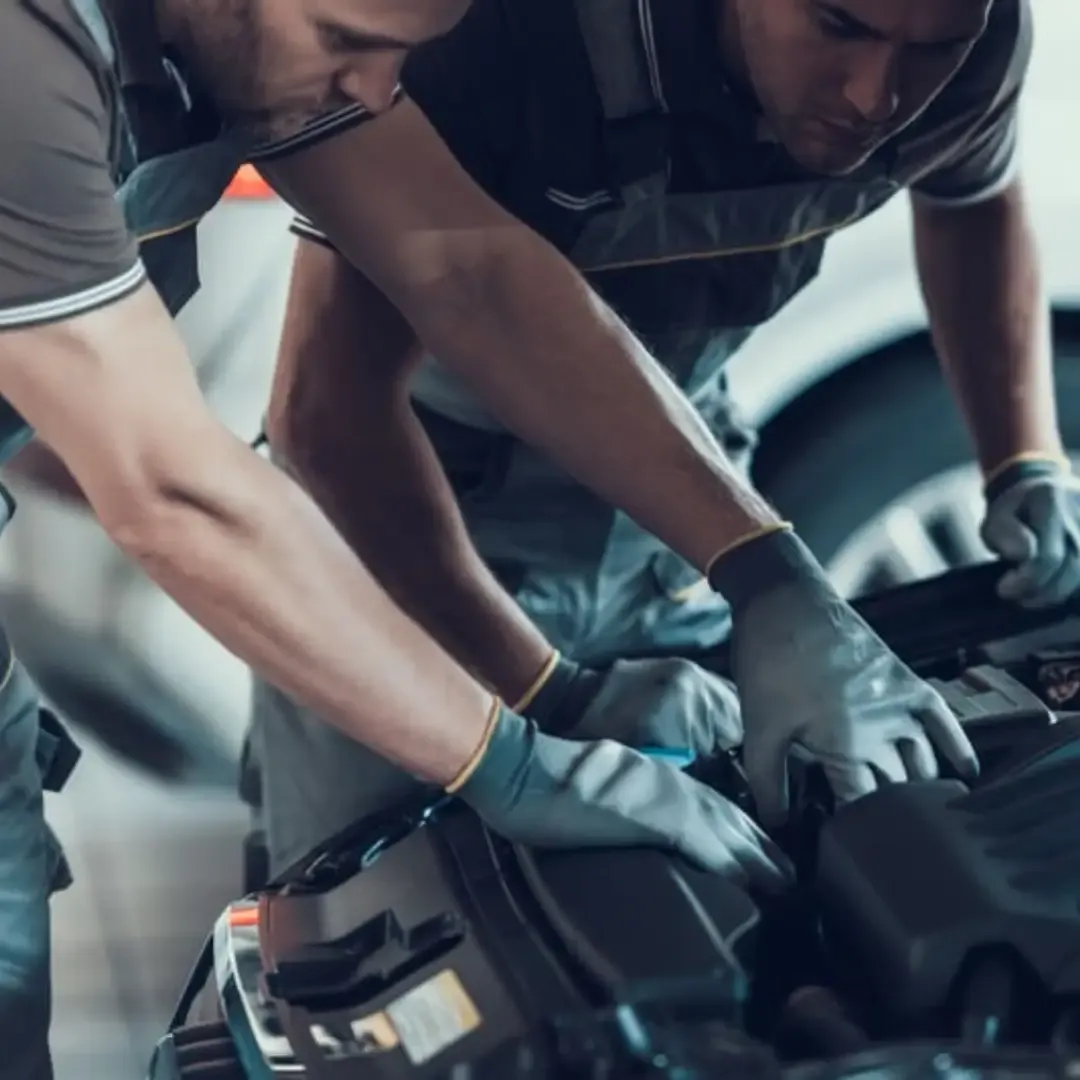 Two mechanics under the bonnet of a car in an MOT testing centre in Birmingham, West Midlands.
